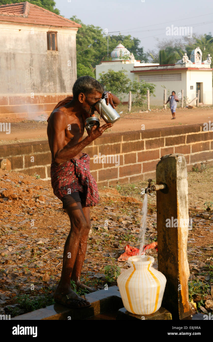 Homme âgé l'eau potable à une fontaine. Banque D'Images