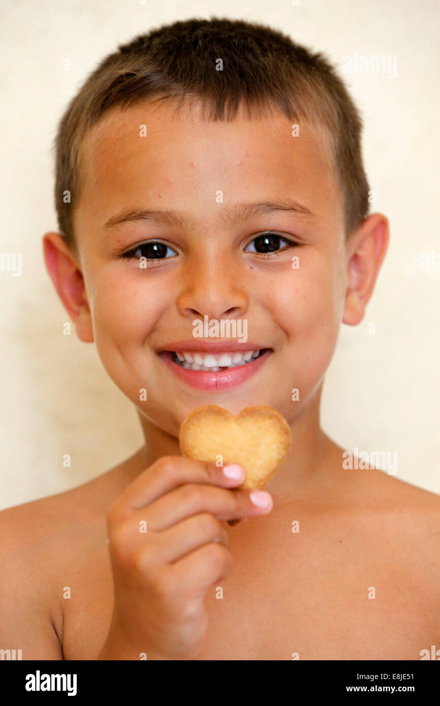 6-année-vieux garçon montrant un biscuit en forme de cœur Banque D'Images
