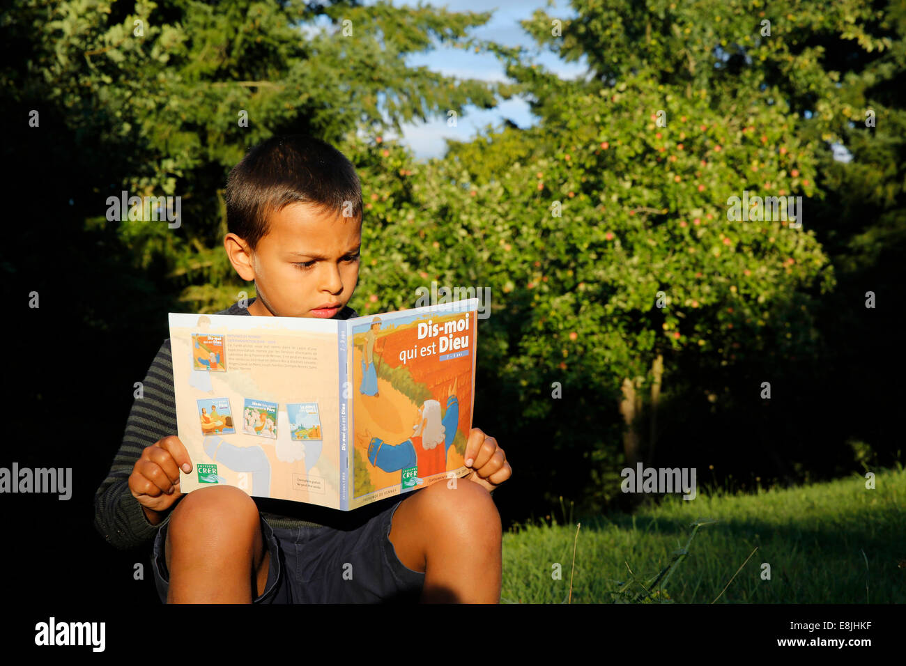 Garçon de 7 ans la lecture d'un livre chrétien pour les enfants Banque D'Images