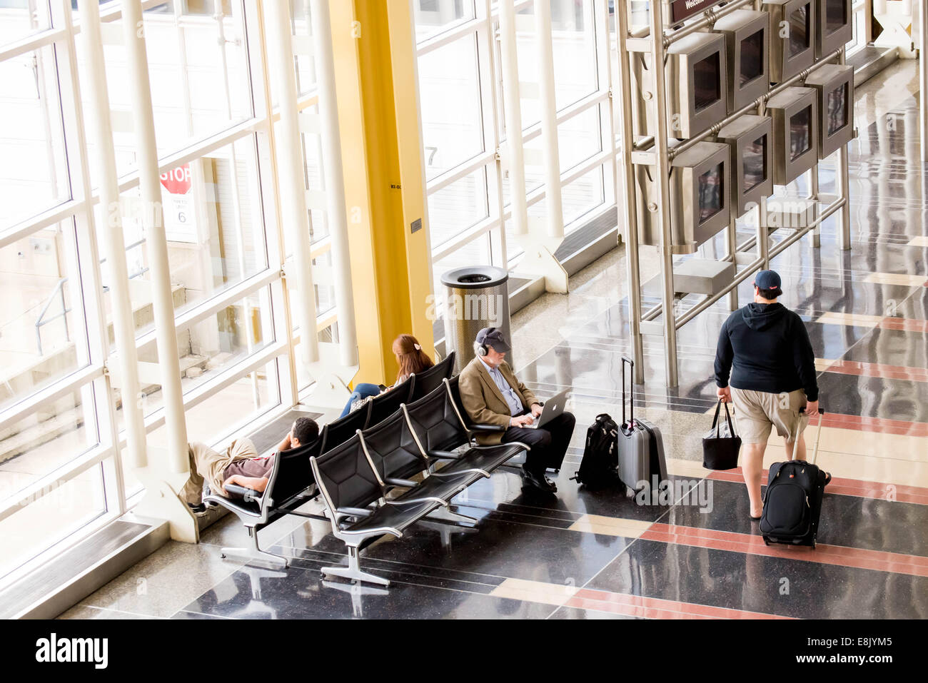 Le DCA, l'Aéroport National Reagan, Washington, DC - Les passagers qui attendent en face d'une fenêtre de l'aéroport intérieur lumineux Banque D'Images