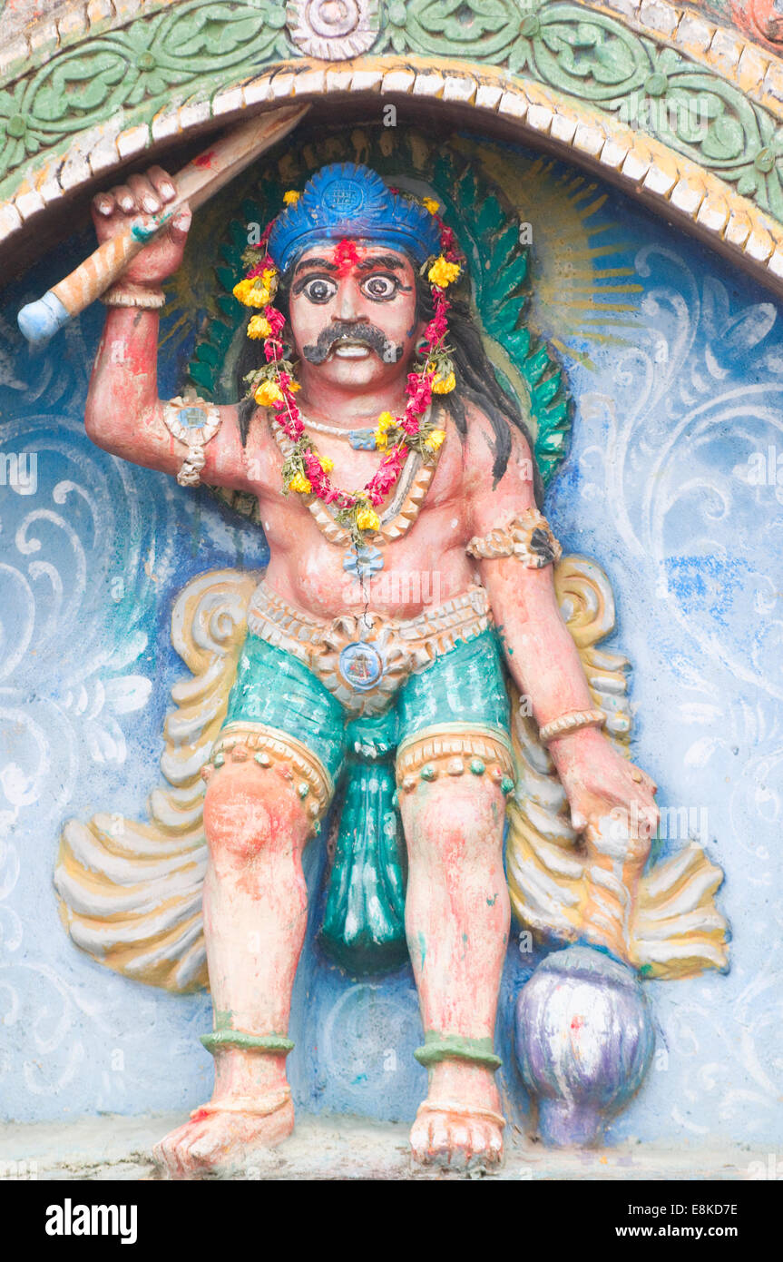 Sanctuaire hindou peint avec une sculpture d'un roi guerrier brandissant une épée, mace et yeux exorbités qui garde l'entrée portes Banque D'Images