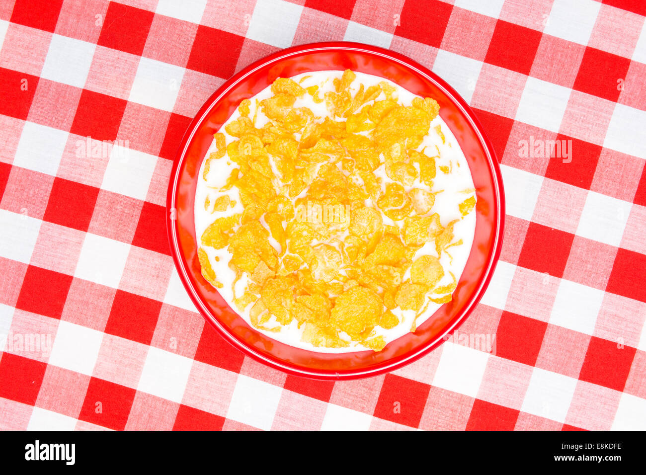 Un bol de cornflakes et rouge sur un classique du lait, rouge à carreaux, prêt comme une nappe repas petit déjeuner. Banque D'Images