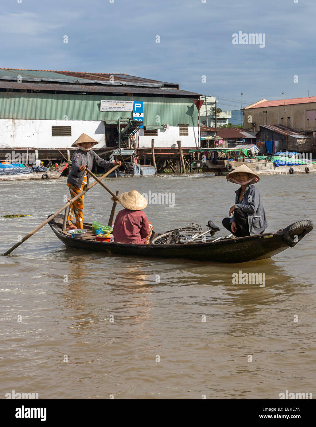 Femme ferries deux autres femmes dans sa petite barque sur la rivière Hau. Banque D'Images