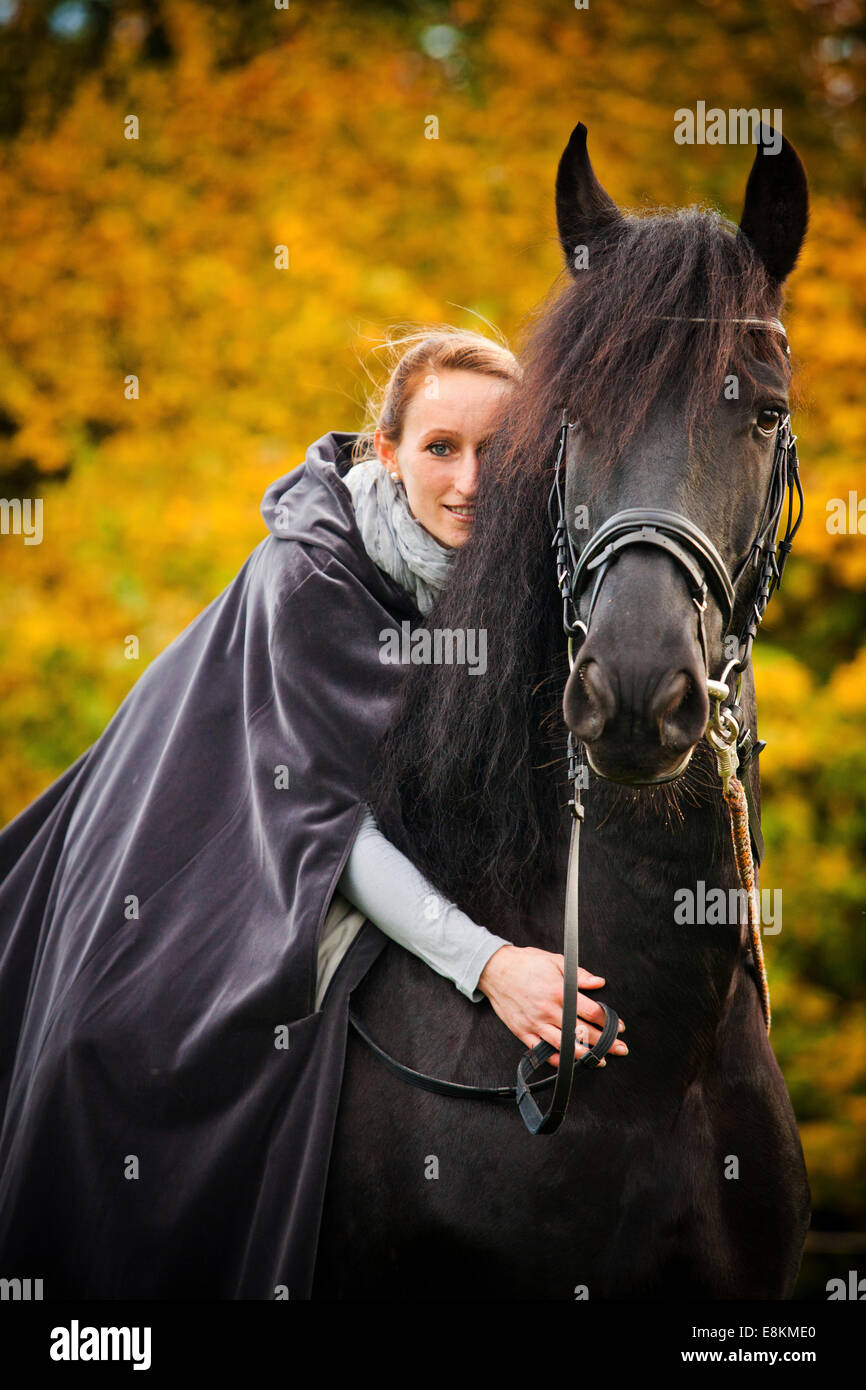 Rider avec le cap sur un Frison, cheval hongre, noir Banque D'Images