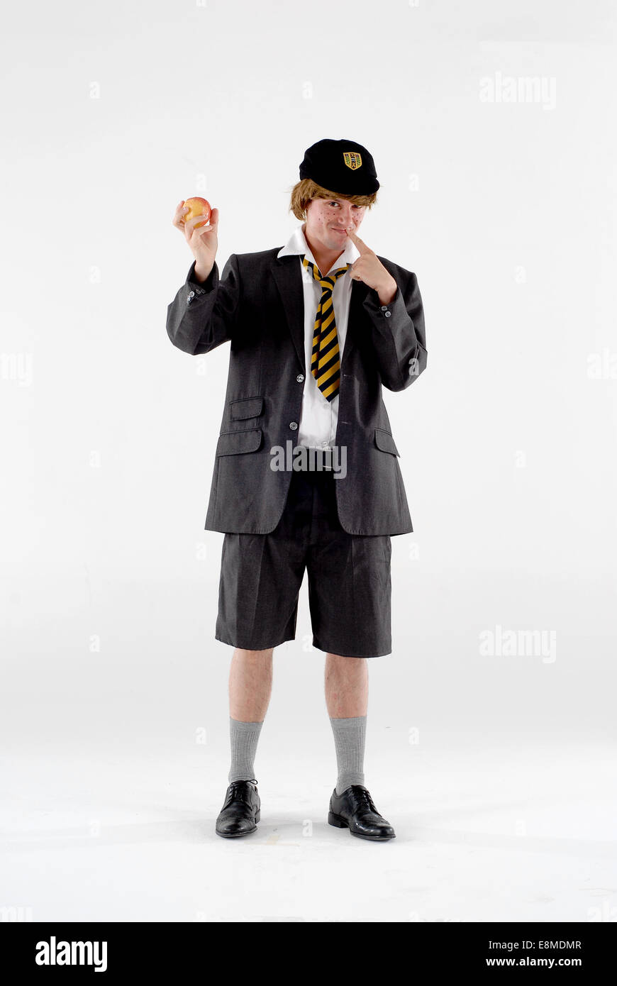 Homme habillé en costume de comédie costumée comme un vilain garçon de l' école, dans l'uniforme scolaire avec chapeau, cravate, short et contre le  blanc Photo Stock - Alamy