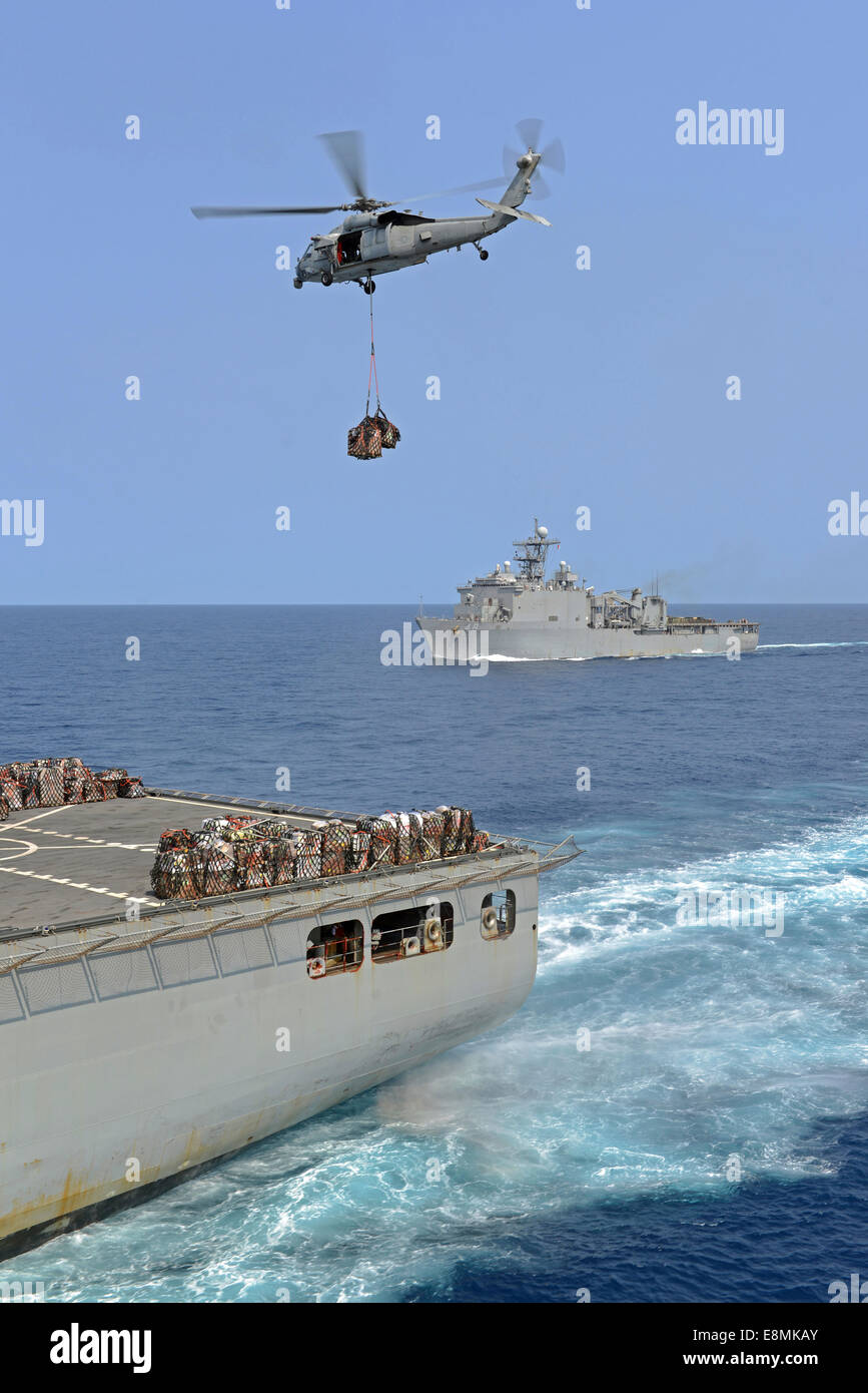 Mer de Chine orientale, le 19 mars 2014 - Un MH-60S Sea Hawk, transferts en hélicoptère des approvisionnements de la commande de transport maritime militaire une cargaison sèche Banque D'Images