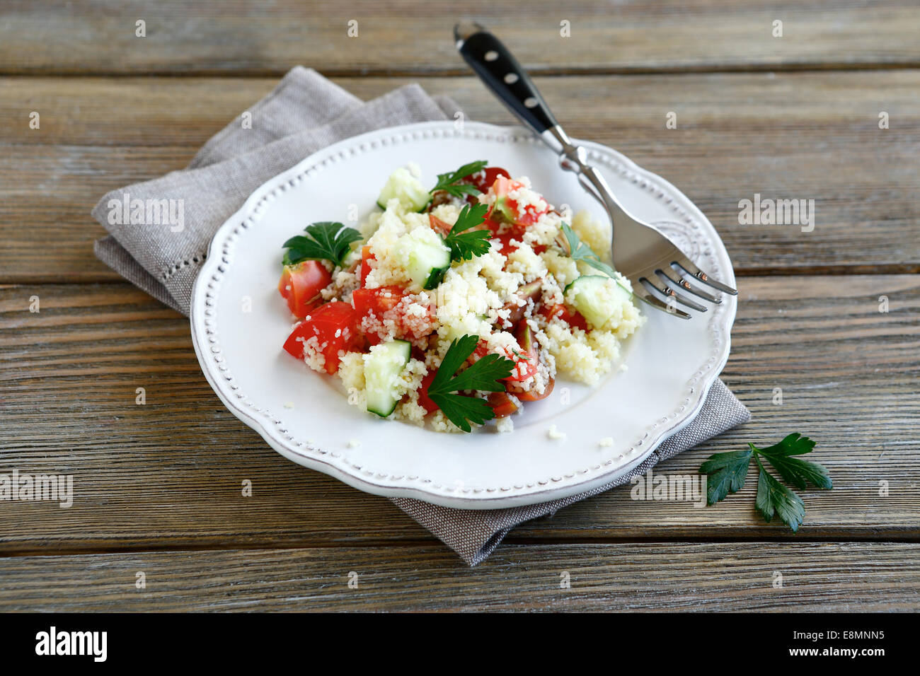 Salade fraîche avec du couscous et les légumes sur une assiette blanche, des aliments nutritifs Banque D'Images