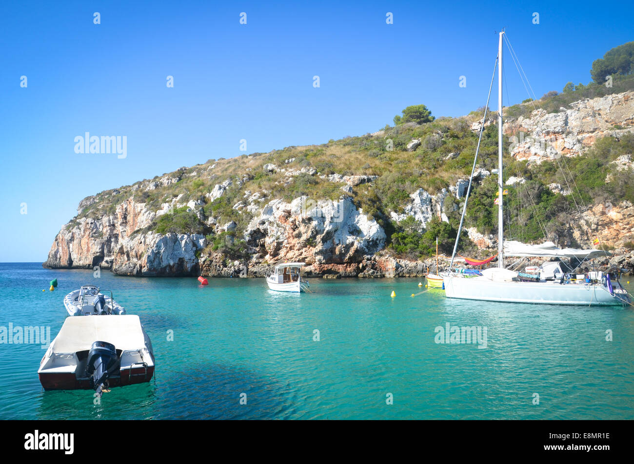 Les bateaux et la plage du petit village de vacances, Es Cala 'n Blanes, sur l'île espagnole de Minorque, dans la mer Méditerranée Banque D'Images