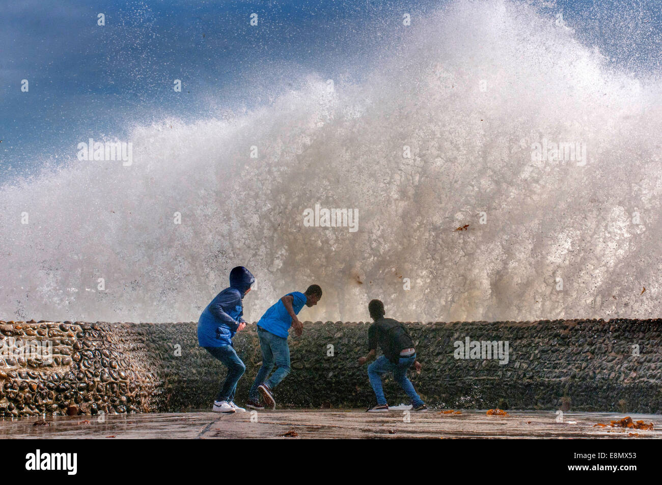 Personnes jouant près de vagues sur le front de mer de Brighton. Banque D'Images