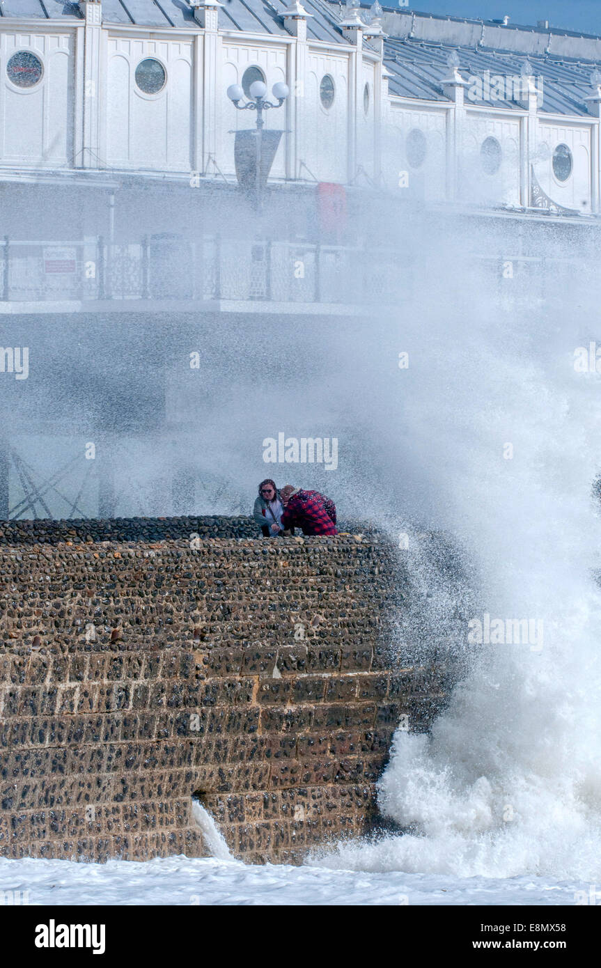 Personnes jouant près de vagues sur le front de mer de Brighton. Banque D'Images