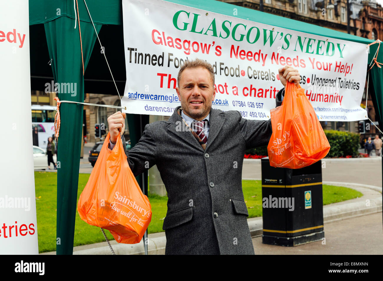 Glasgow, Ecosse. Oct 11, 2014. Andrew Carnegie, 45 ans, de Tollcross à Glasgow, qui ont mis en place l'organisme de bienfaisance du comptoir alimentaire 'Glasgow nécessiteux' mis en place d'un décrochage à George Square, Glasgow city centre, à l'extérieur de la ville, chambres, avec l'intention de percevoir les cotisations et attire aussi l'attention sur l'inégalité sociale et les besoins des pauvres. Plusieurs passants- par contribué à sa charité par la remise de sacs de nourriture, y compris Colin Boyd, 38 ans. Le Directeur de l'entreprise de Kilwinning. Credit : Findlay/Alamy Live News Banque D'Images