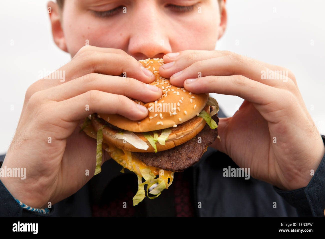 Un adolescent de manger un hamburger Big Mac de McDonald's. Banque D'Images