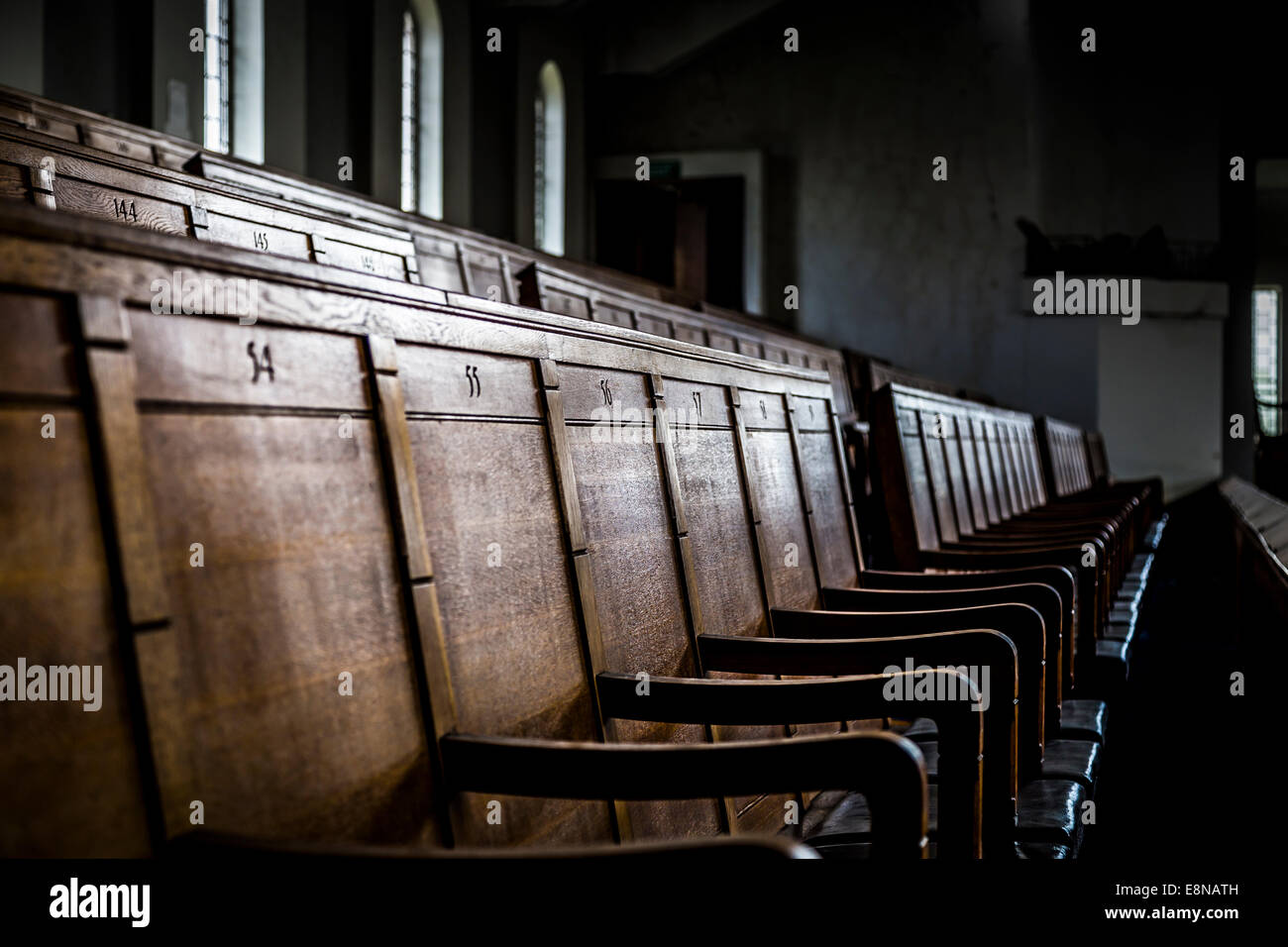 Bancs en bois numérotées dans un bâtiment fermé et abandonné. Profondeur de champ avec l'accent sur siège numéro 56. Banque D'Images