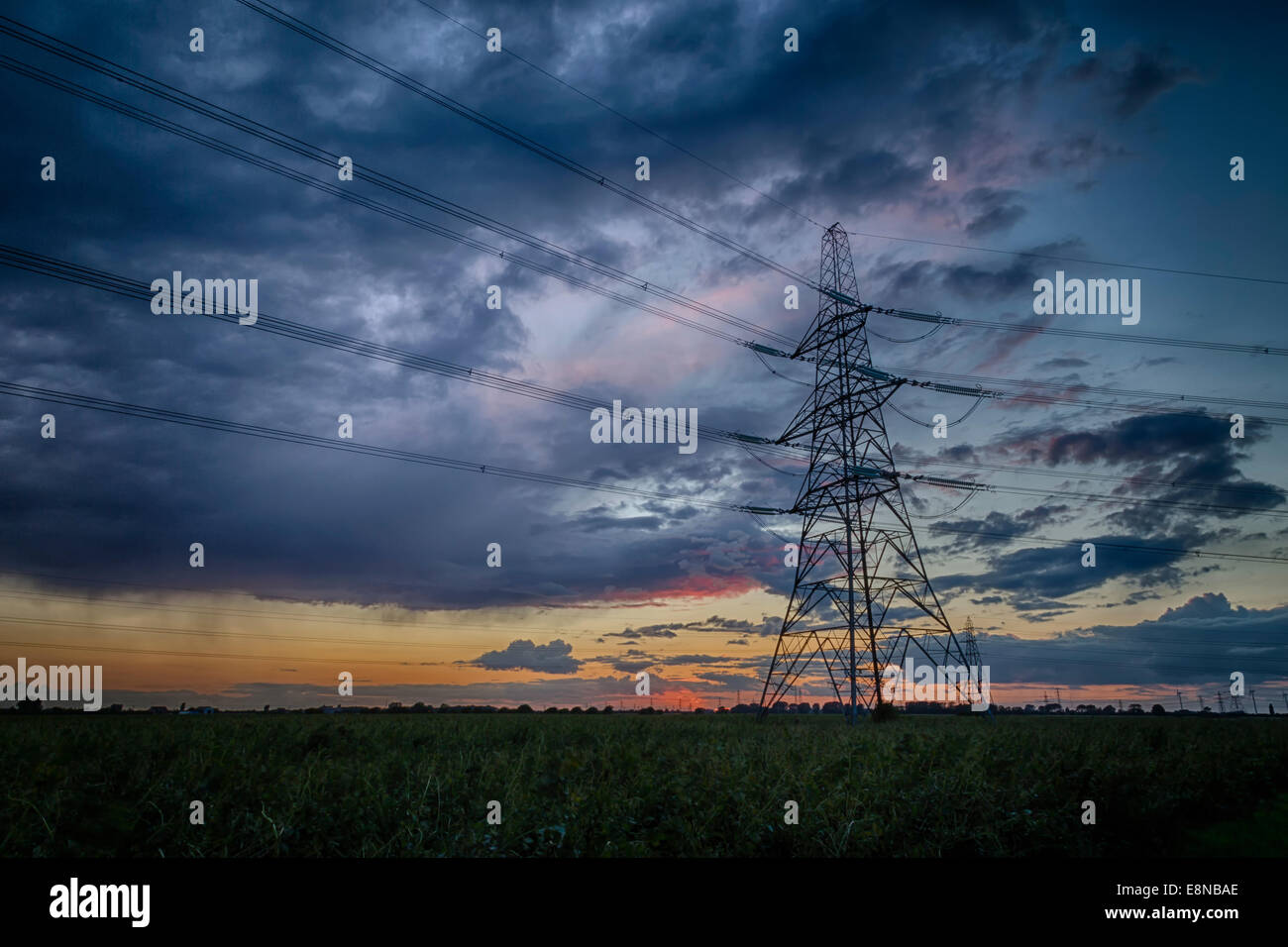 Pylône de l'électricité contre une silhouette bleu, violet et orange ciel au crépuscule. Les nuages de tempête à l'horizon. Banque D'Images