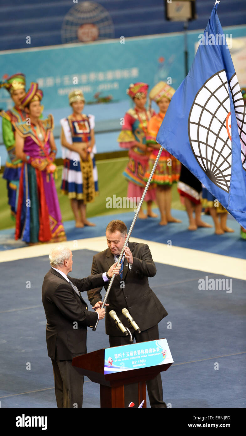 Nanning, Chine, région autonome Zhuang du Guangxi. 12 octobre, 2014. FIG Président Bruno Grandi (L) les mains sur la figure d'un drapeau à un représentant de Glasgow, Écosse, Royaume-Uni, la ville hôte des 46e Championnats du monde de gymnastique, lors de la cérémonie de clôture des 45e Championnats du monde de gymnastique à Nanning, capitale de la Chine du Sud, région autonome Zhuang du Guangxi, le 12 octobre 2014. Credit : Huang Xiaobang/Xinhua/Alamy Live News Banque D'Images