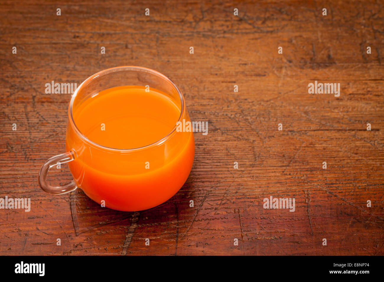 Une tasse en verre de jus de carotte fait maison sur une table en bois grunge Banque D'Images