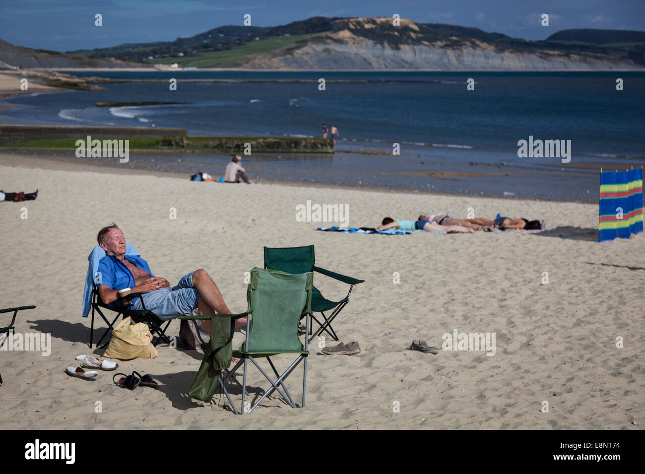 Homme d'âge moyen et se détendre dormir sur une chaise pliante sur la plage de Lyme Regis. Banque D'Images