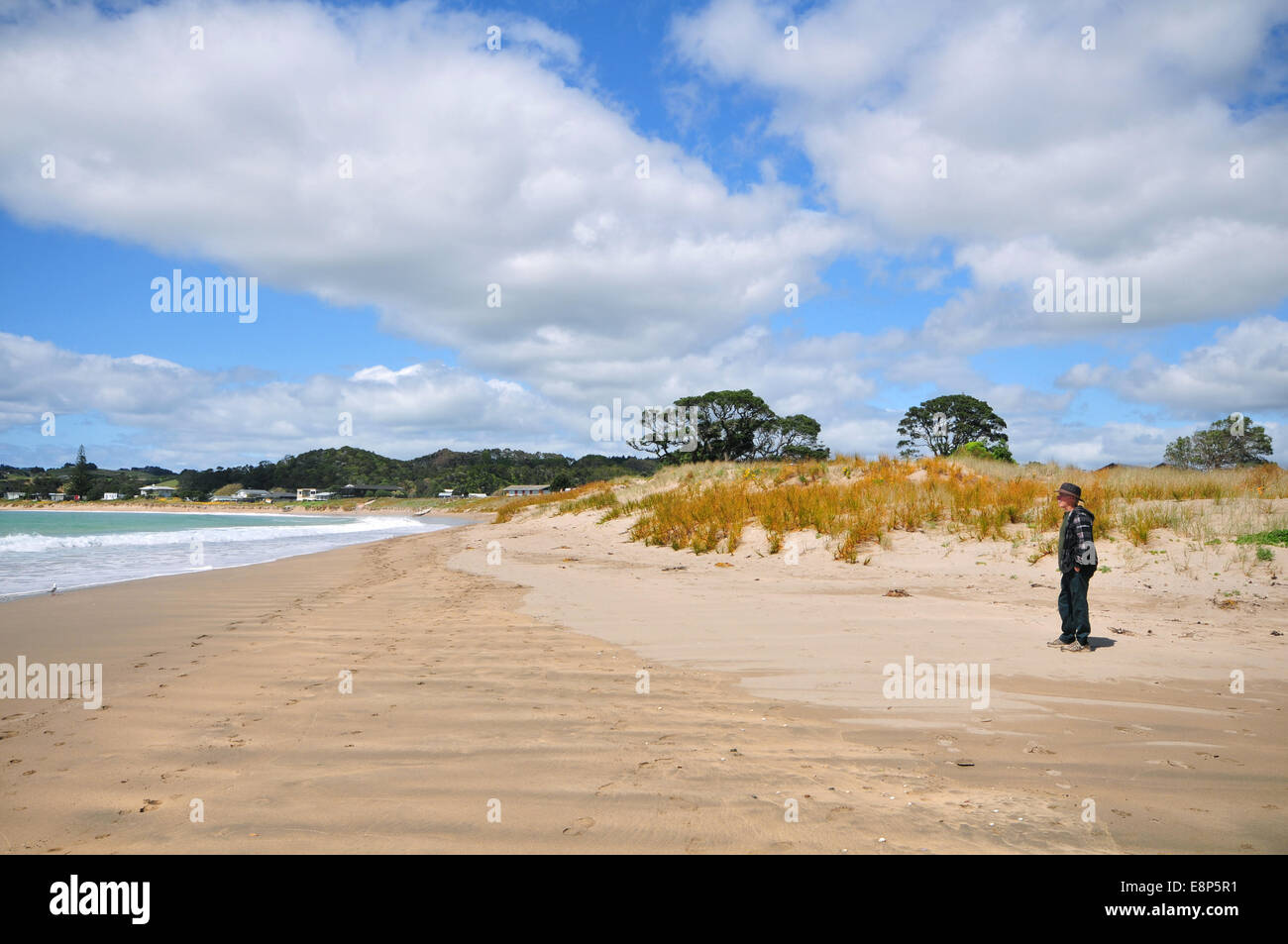 Homme seul sur la plage de sable dans la baie à marée basse Matapouri Banque D'Images