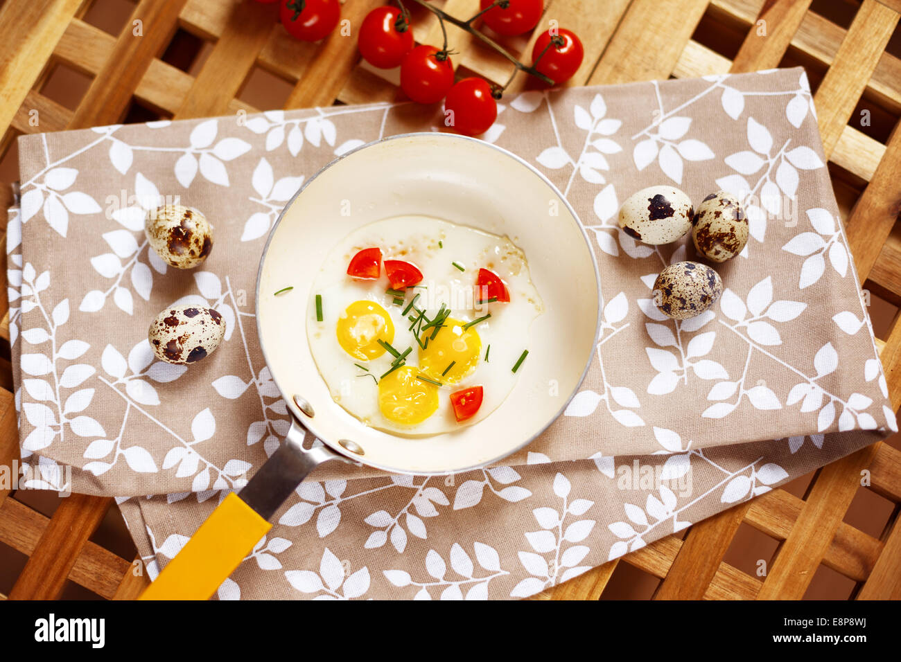 Table du petit déjeuner avec des œufs au plat. Oeufs de caille, un peu jaune poêle, tomates cerise servi sur table en bois. Vue d'en haut. Banque D'Images