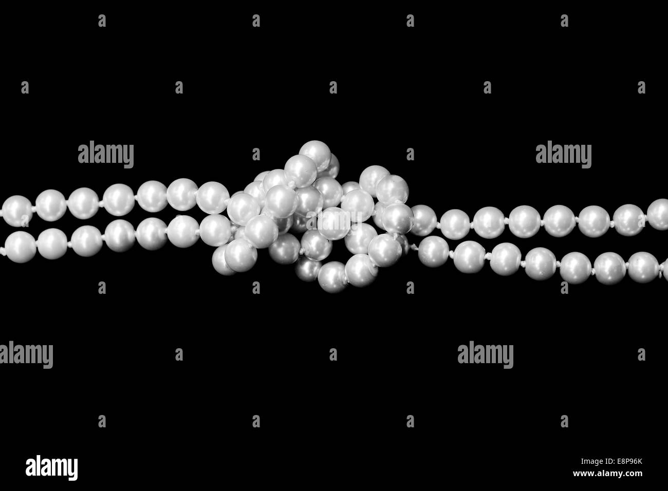 Double fil de perles attachées dans un noeud sur fond noir Banque D'Images