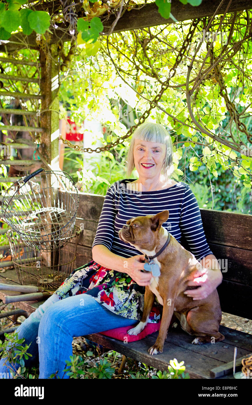 Senior woman sitting on bench with dog Banque D'Images