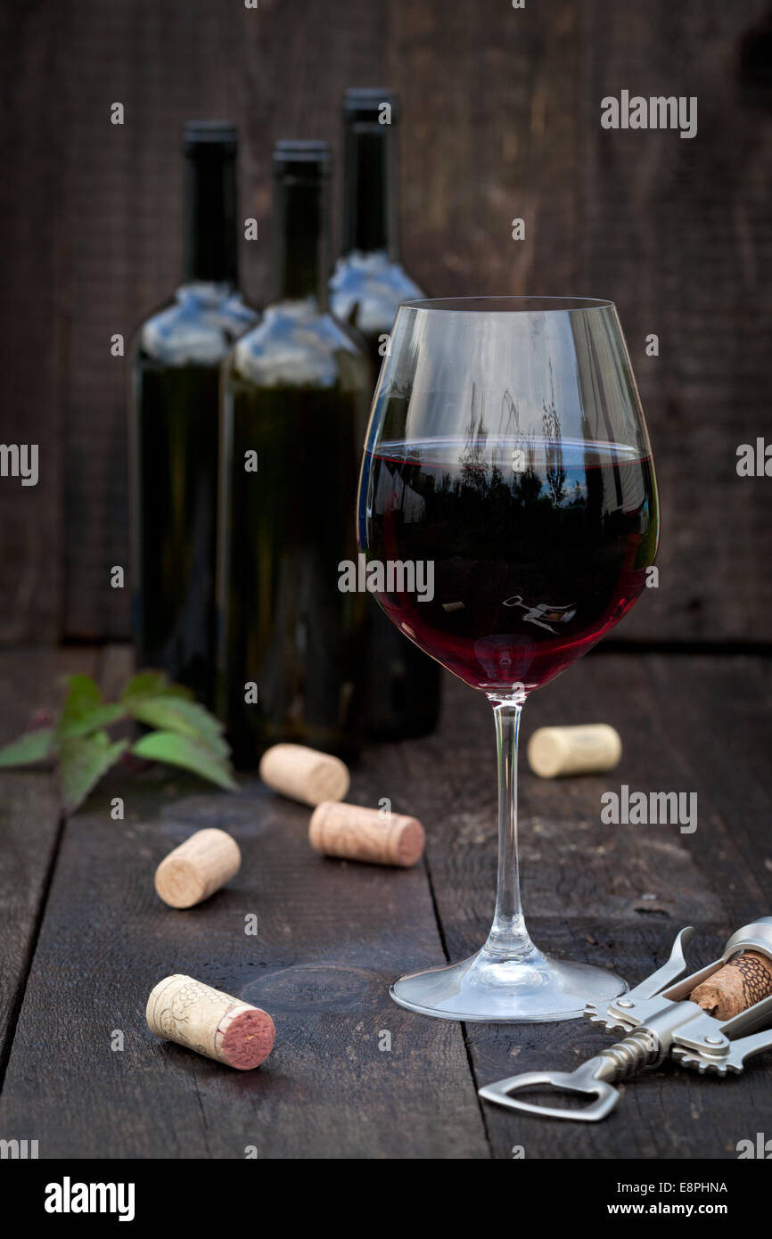 Verre de vin rouge avec des bouchons sur la vieille table en bois Banque D'Images