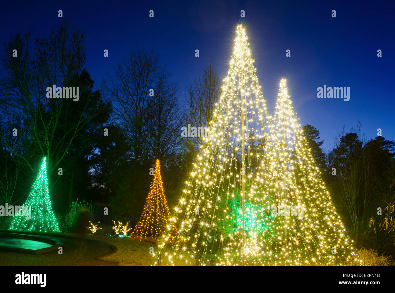 Les arbres de Noël en plein air ont été créés par décorer avec du rouge, blanc et vert s'allume et tourné contre un brillant ciel bleu. Banque D'Images