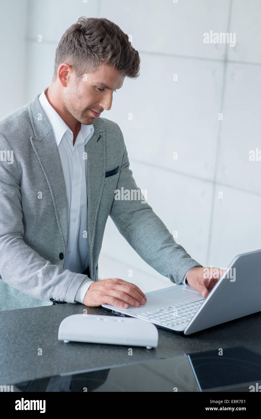 L'homme élégant assis à taper sur un ordinateur portable Banque D'Images