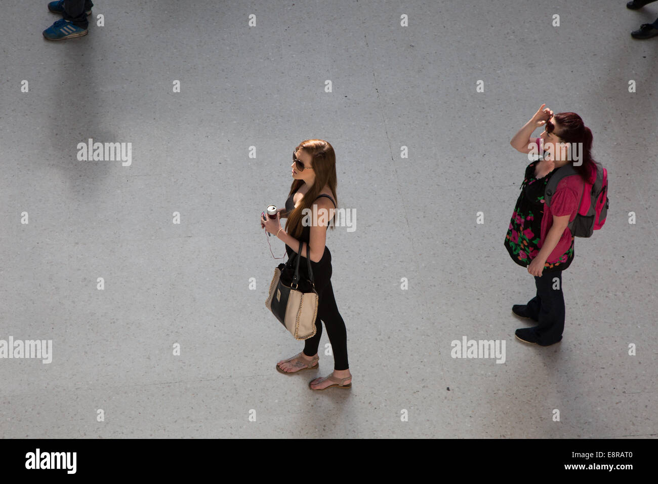 Les passagers qui attendent les femmes pour les informations sur la plate-forme à la gare de Brighton. Banque D'Images