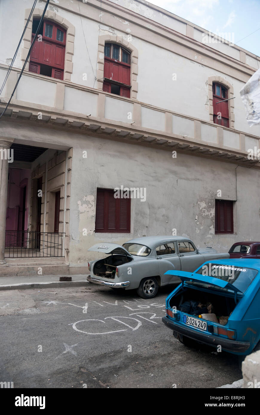 Une scène de rue à l'arrière typique d'un centre de quartier de La Havane. Voitures anciennes et leurs malles ouvrir en attente de réparations. Banque D'Images