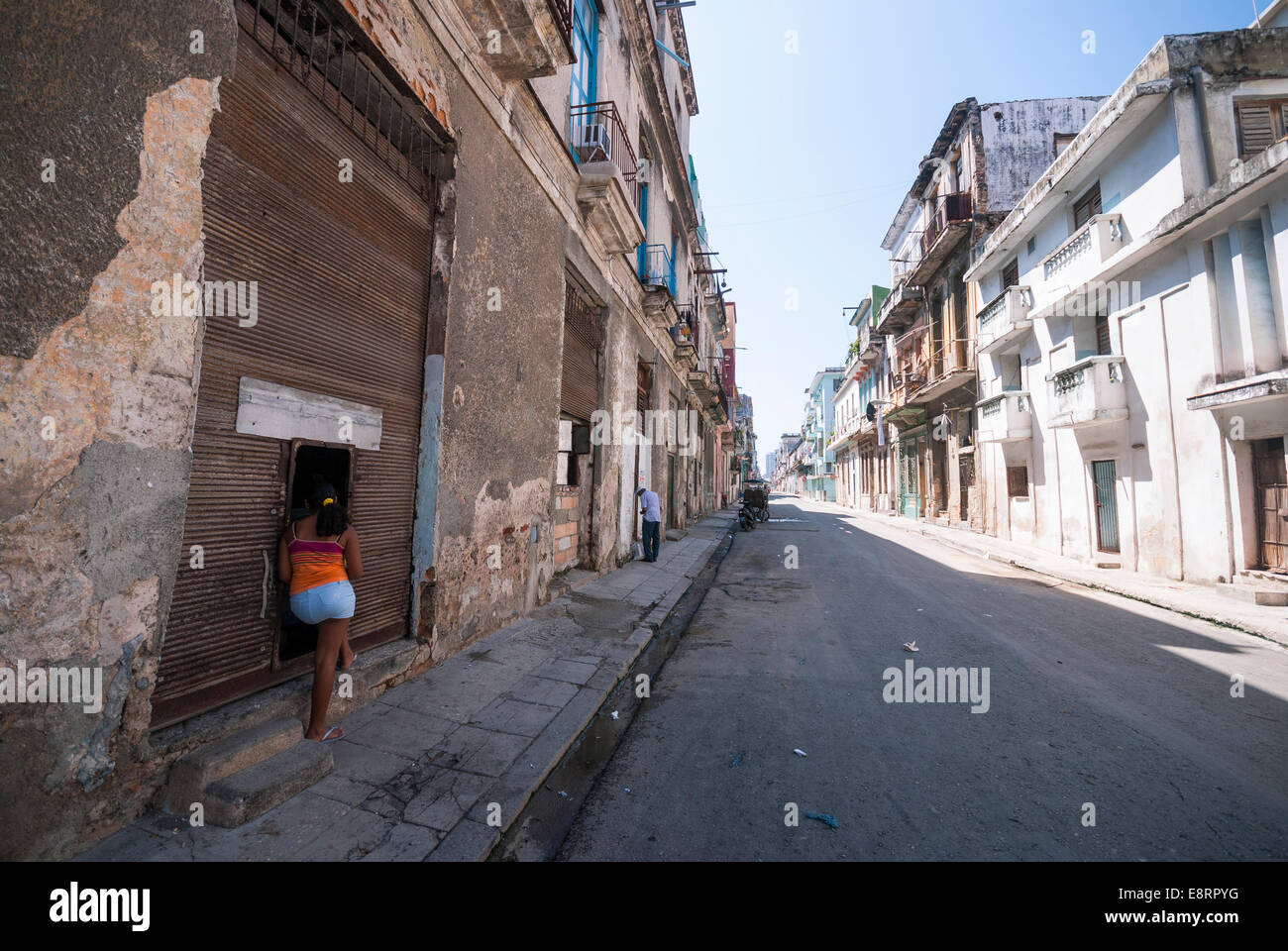 Une femme parle à un(e) ami(e) à travers une porte ouverte dans un quartier de La Havane. Banque D'Images