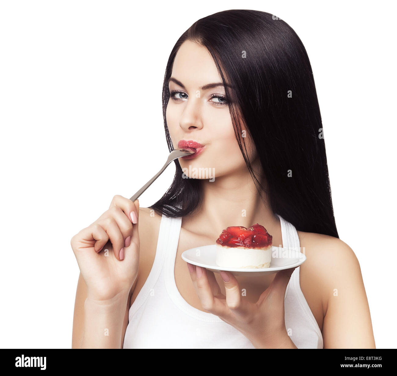 Femme de lécher avec cuillère gâteau sur fond blanc Banque D'Images