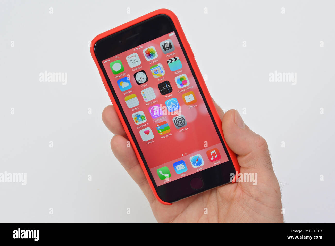 Apple iPhone 6 téléphone mobile en cas rouge tenue à une main d'homme sur un fond blanc. Banque D'Images