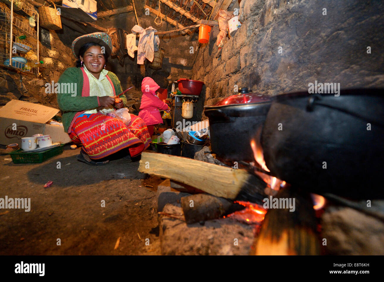 Jeune femme la cuisson sur un feu ouvert dans sa cuisine traditionnelle, Union européenne, Potrero Quispillacta, Ayacucho, au Pérou Banque D'Images