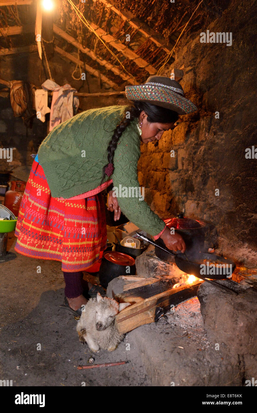 Jeune femme la cuisson sur un feu ouvert dans sa cuisine traditionnelle, Union européenne, Potrero Quispillacta, Ayacucho, au Pérou Banque D'Images