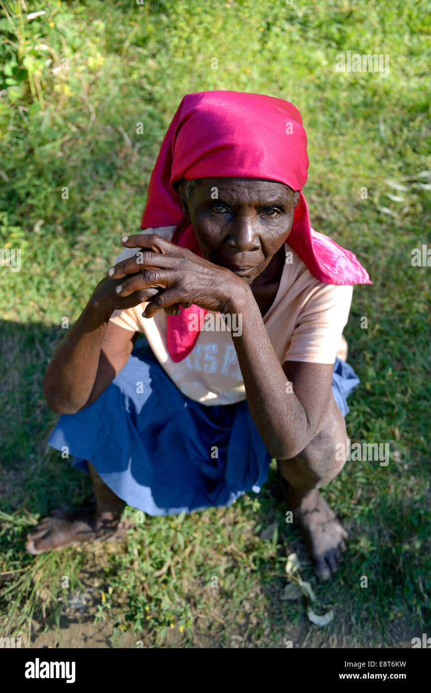 Vieille Femme assise dans l'herbe, Tchawa, LÉOGÂNE, Haïti Banque D'Images