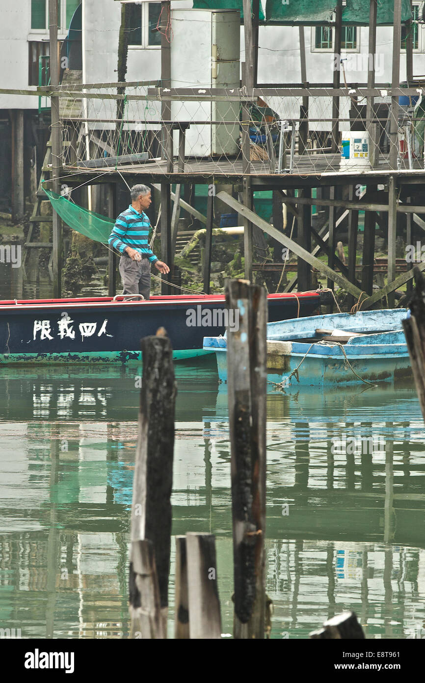 Pêcheur à bord d'un petit bateau de pêche dans le rustique village de pêcheurs Chinois Tai O sur l'île de Lantau, à Hong Kong. Banque D'Images