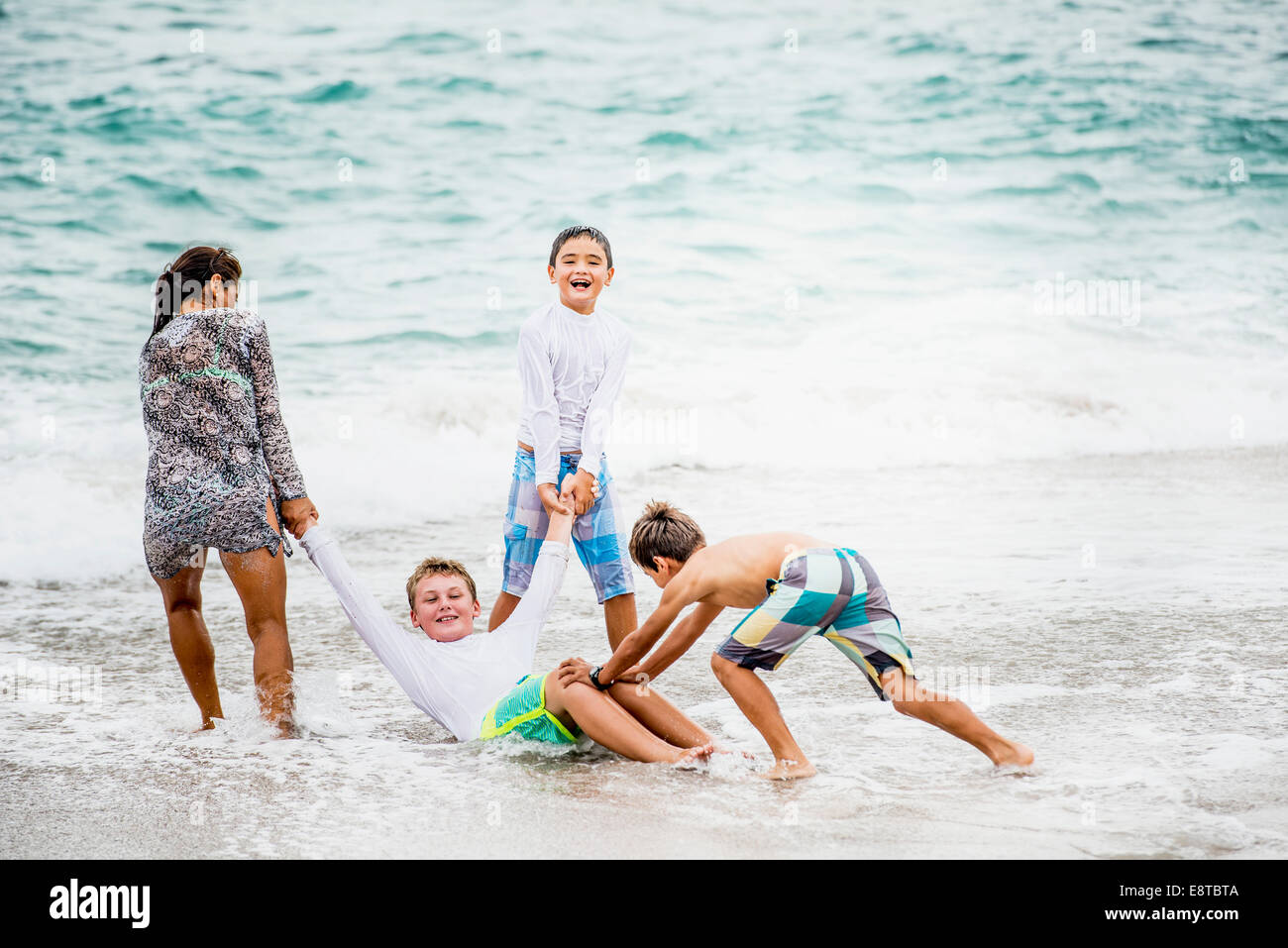 Famille de jouer ensemble dans les vagues sur la plage Banque D'Images