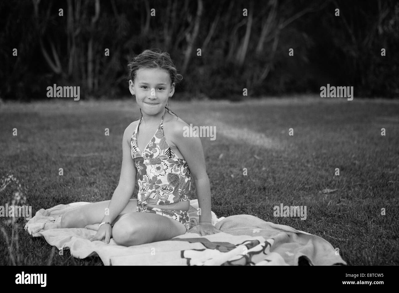 Caucasian girl sitting on towel in backyard Banque D'Images