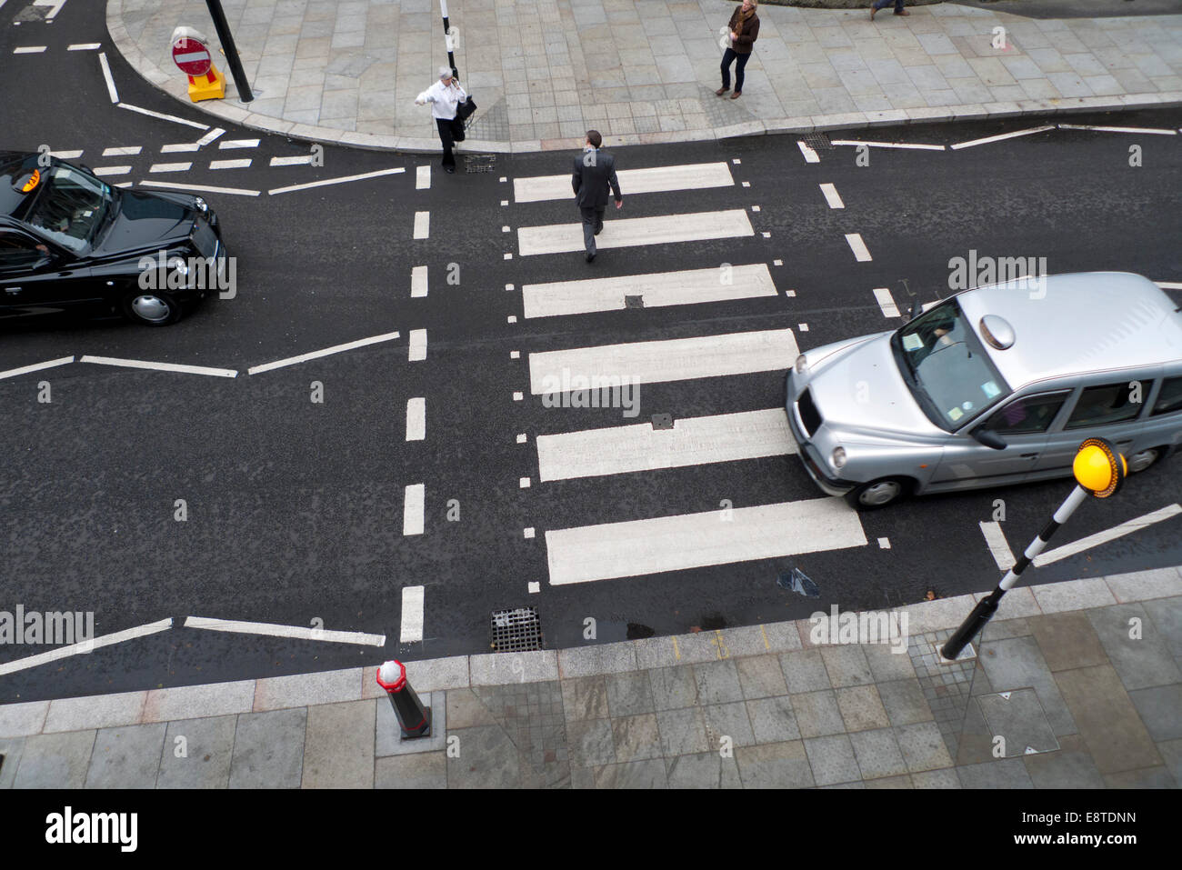 Vue en hauteur des taxis en attente d'une personne piétonne traversant la route à un passage de zébra sur Beech Street avec des marques de route à rayures blanches près du Barbican Center dans la ville de Londres Royaume-Uni KATHY DEWITT Banque D'Images