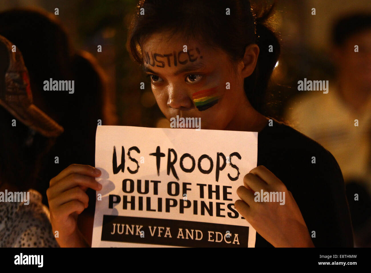 Manille, Philippines. 14Th Oct, 2014. Un militant est titulaire d'une affiche appelant à la redirection de l'Accord de coopération de défense (EDCA) lors d'un rallye candlelighting à Manille, Philippines, le 14 octobre, 2014. Le gouvernement philippin a promis mardi de la justice pour un Philippin les transgenres, retrouvé mort dans un hôtel à Olongapo City dans le nord des Philippines. Un U.S. Marine, identifié comme soldat de première classe Joseph Scott Pemberton, a été étiqueté comme un possible suspect dans l'assassinat de Jeffrey Laude. Credit : Rouelle Umali/Xinhua/Alamy Live News Banque D'Images