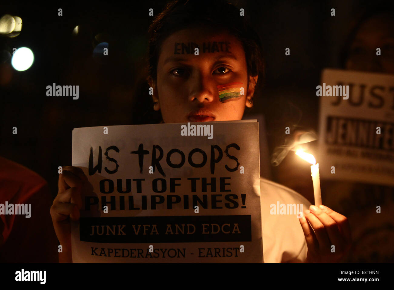 Manille, Philippines. 14Th Oct, 2014. Un militant est titulaire d'une affiche appelant à la redirection de l'Accord de coopération de défense (EDCA) lors d'un rallye candlelighting à Manille, Philippines, le 14 octobre, 2014. Le gouvernement philippin a promis mardi de la justice pour un Philippin les transgenres, retrouvé mort dans un hôtel à Olongapo City dans le nord des Philippines. Un U.S. Marine, identifié comme soldat de première classe Joseph Scott Pemberton, a été étiqueté comme un possible suspect dans l'assassinat de Jeffrey Laude. Credit : Rouelle Umali/Xinhua/Alamy Live News Banque D'Images