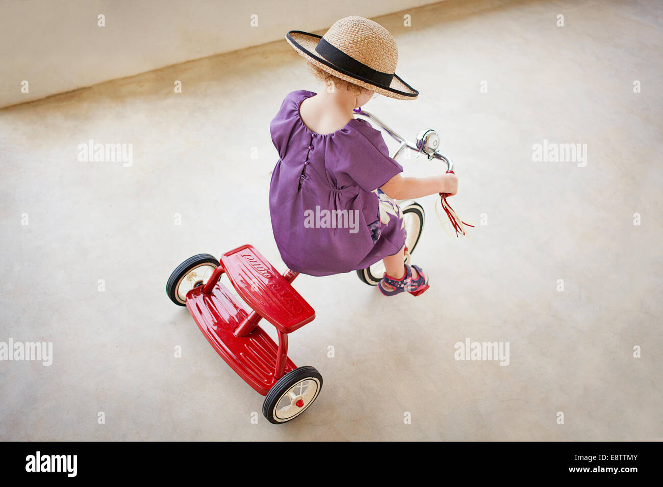 Joli trois ans dans un chapeau sur un tricycle Banque D'Images