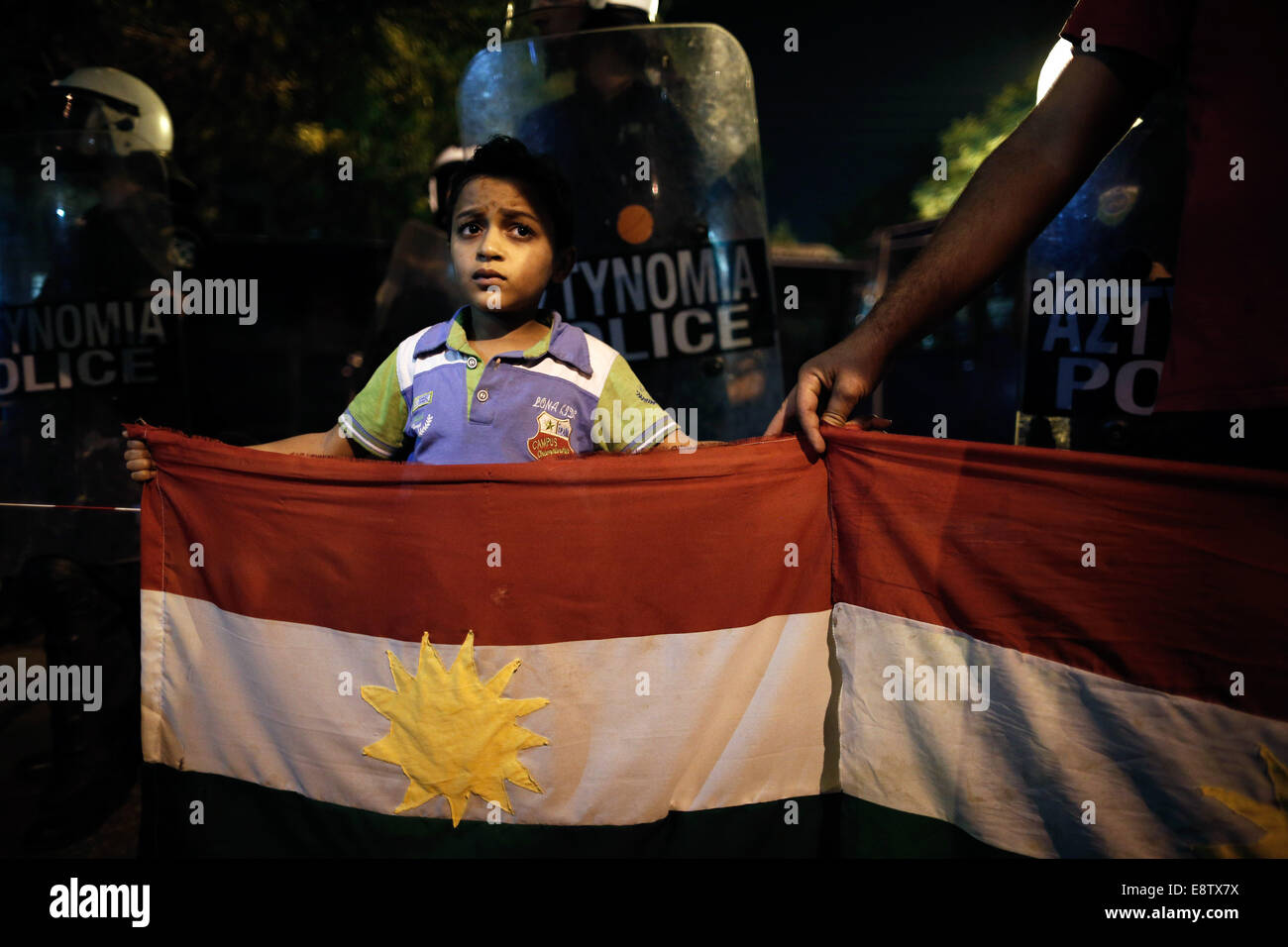 Thessalonique, Grèce. 14 octobre, 2014. Un enfant kurde détient un drapeau kurde en face d'agents de police anti-émeute qui bloquent l'entrée du consulat de Turquie au cours d'une manifestation pro-kurde contre les attaques lancées par l'État islamique d'insurgés ciblant la ville syrienne de Kobane à Thessalonique, Grèce le 14 octobre 2014. Credit : Konstantinos Tsakalidis/Alamy Live News Banque D'Images