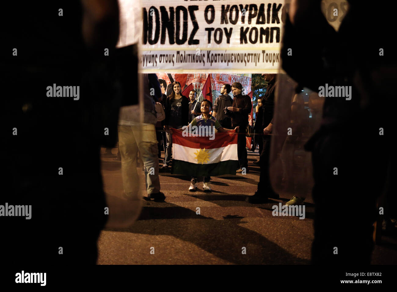 Thessalonique, Grèce. 14 octobre, 2014. Un enfant kurde détient un drapeau kurde en face d'agents de police anti-émeute qui bloquent l'entrée du consulat de Turquie au cours d'une manifestation pro-kurde contre les attaques lancées par l'État islamique d'insurgés ciblant la ville syrienne de Kobane à Thessalonique, Grèce le 14 octobre 2014. Credit : Konstantinos Tsakalidis/Alamy Live News Banque D'Images