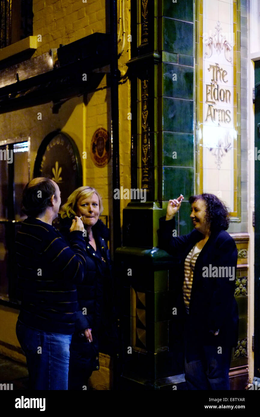 Trois personnes se tiennent à l'extérieur pour une cigarette à un pub anglais traditionnel l'Eldon arms uk angleterre southsea Banque D'Images