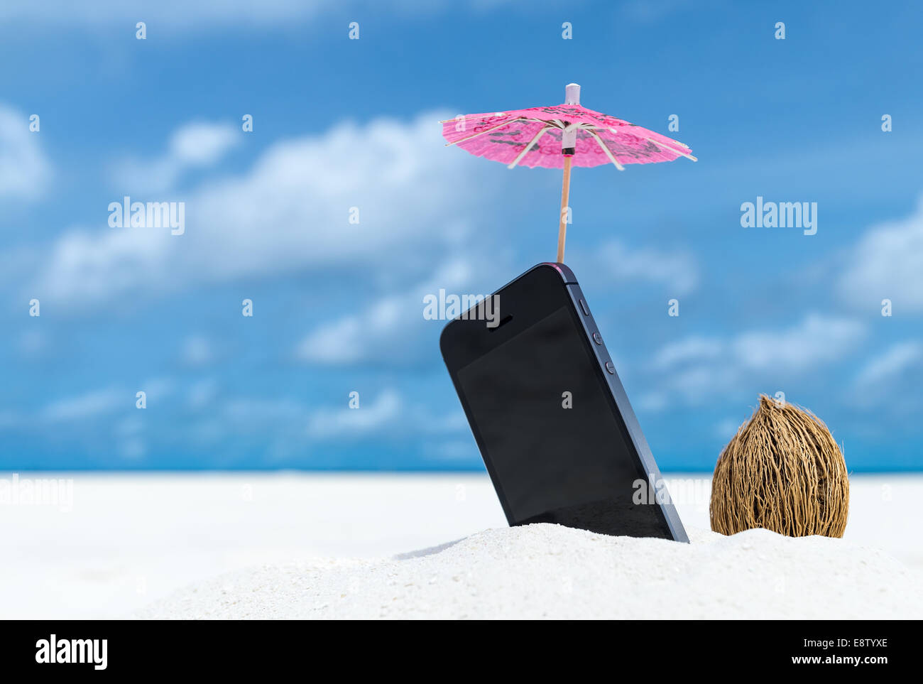 Téléphone mobile et parapluie cocktail sur la plage avec la mer en arrière-plan Banque D'Images