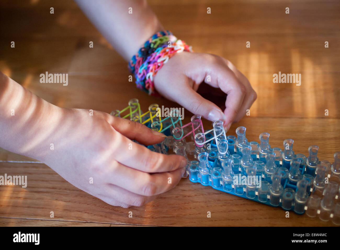 Une petite fille travaille sur le tissage d'un bracelet sur son métier à Arc -en-ciel, un jouet loom utilisée pour tisser des bandes de caoutchouc en bracelets  et charms Photo Stock - Alamy