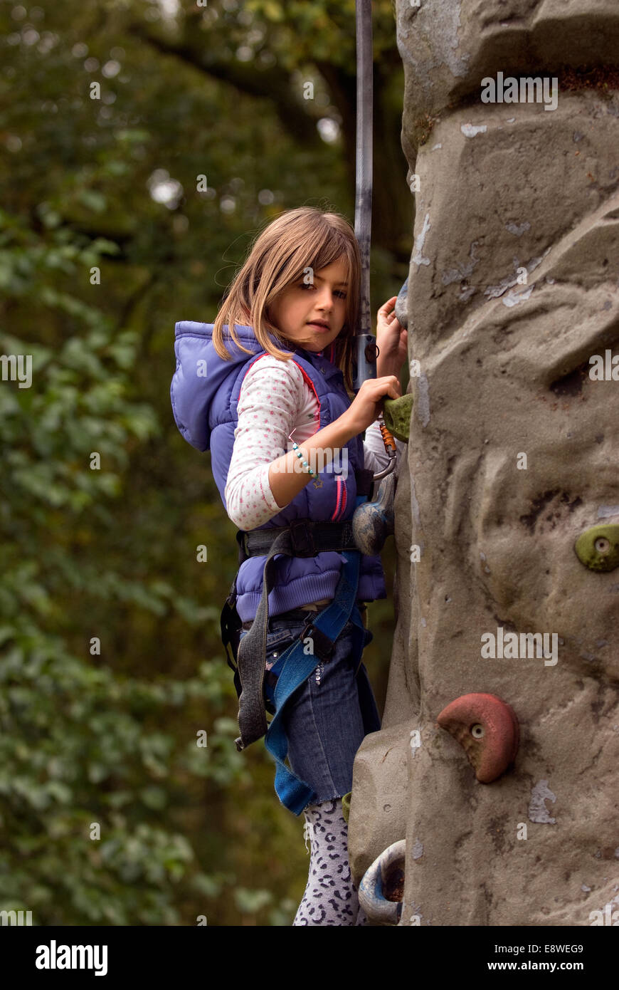 8 ans, fille d'essayer le mur d'escalade dans une ferme journée portes ouvertes, blackmoor, Hampshire, Royaume-Uni. Banque D'Images