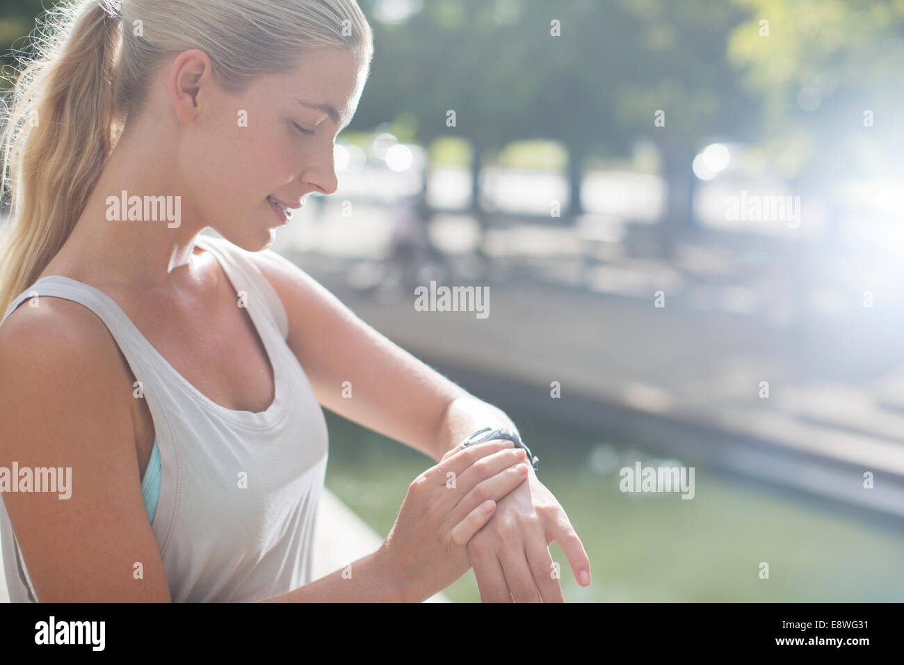 Woman looking at watch avant l'exercice on city street Banque D'Images